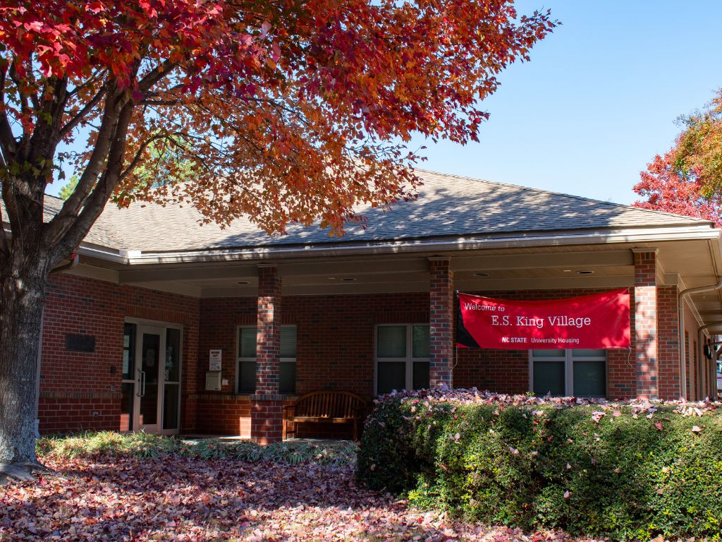 Exterior of E.S. King Village community building with a "Welcome to E.S. King Village" banner
