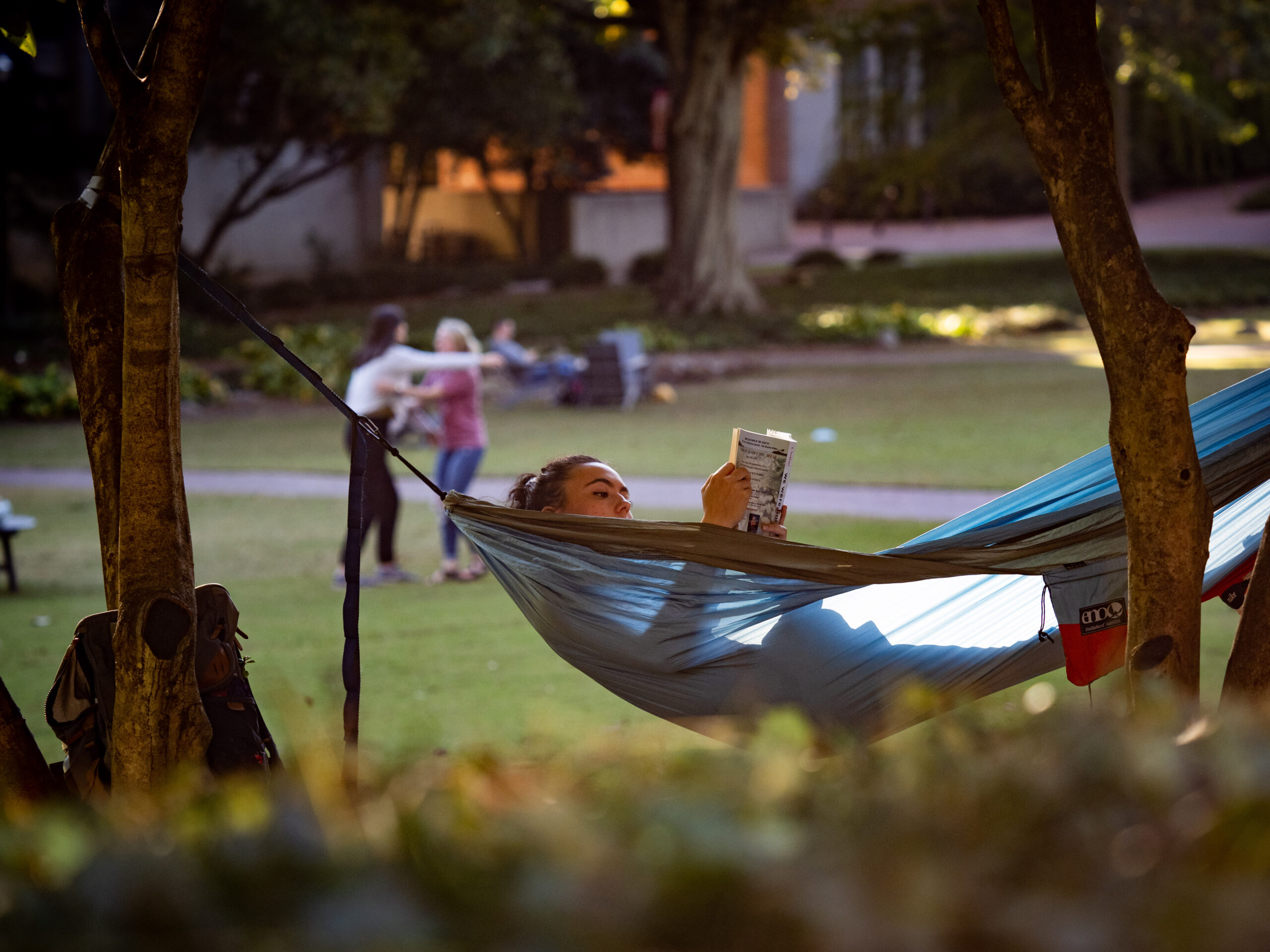 A student reads a book while kicking back in a hammock on the court of North Carolina. Photo by Marc Hall